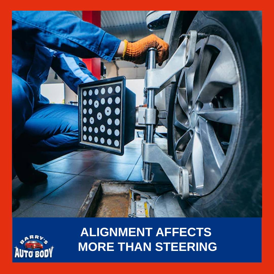 Technician performing a four-wheel alignment on a vehicle using computerized alignment equipment.